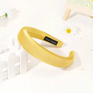 Close-up of bright yellow satin headband with premium silk finish and Hand Made label