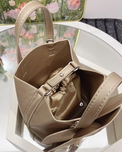 Detailed view of champagne gold bucket bag with satin drawstring liner and leather texture