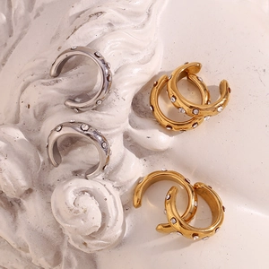 Macro shot of 18K gold and silver C-shaped ear cuffs with sparkling crystals on plaster