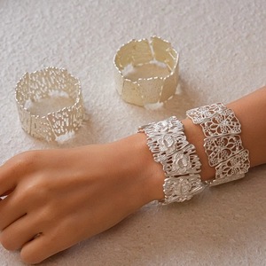 Detailed view of silver open cuff bracelet with matte floral and geometric hollow patterns