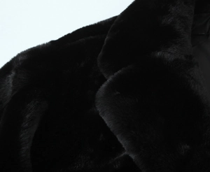 Détail du col et de l'épaule d'un manteau en fausse fourrure noire à texture douce