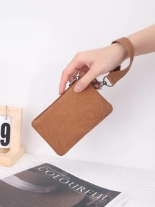 Brown washed canvas coin purse with wrist strap held against a lifestyle background