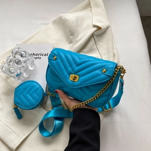 Detail of bright blue quilted shoulder bag with chain strap and matching coin purse