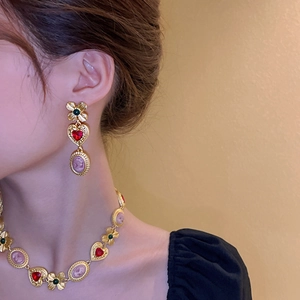 Close-up of vintage gold necklace and earrings with red heart gems and pink portrait cameos