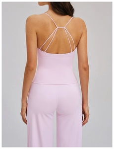 Détail des bretelles croisées dans le dos d'un haut de yoga rose pâle en tissu brossé