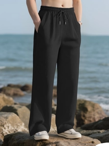 Detail of black pleated wide-leg pants featuring elastic waistband with adjustable drawstrings
