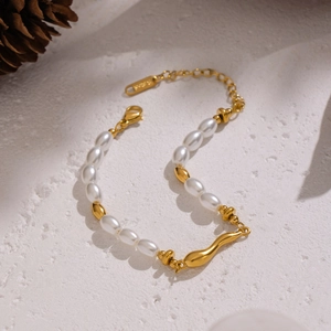 Baroque pearl bracelet with 18K gold plated irregular beads on a textured neutral background