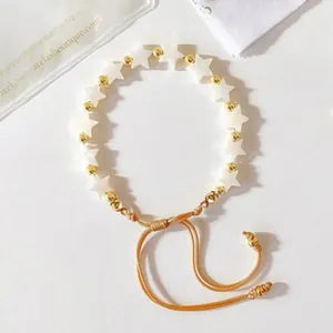 Detail of star-shaped beads and gold accents on a handmade woven adjustable bracelet