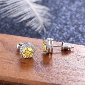 Macro view of round yellow gemstone stud earrings with halo diamond setting on wood