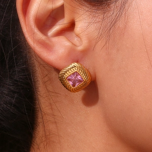 Macro shot of gold plated stud earring featuring a square pink zircon and twill texture