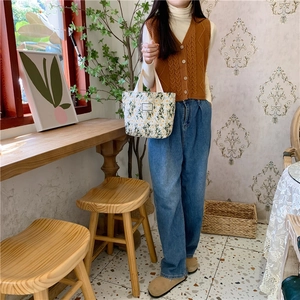 Detail of floral canvas tote bag featuring embroidered daisy pattern in a cozy indoor setting
