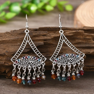 Bohemian silver earrings with colorful bead tassels and bells on a rustic wood background