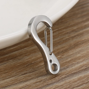 Silver stainless steel lobster clasp on white ceramic dish with wood background