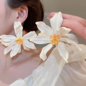 Macro detail of large white acrylic flower earring with orange beaded center