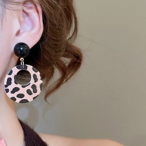 Detail showing vintage leopard print resin earrings worn by a model in a minimal setting