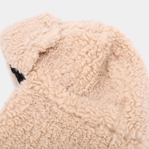 Close-up of warm beige thick sherpa fleece fabric showing soft texture of trapper hat