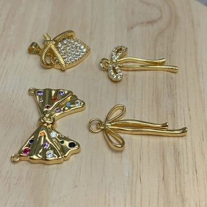 Gold bow and bag charms with micro-pave zircons on a wooden texture background