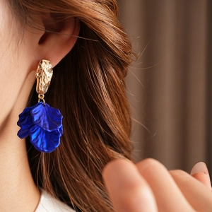 Detail of vintage gold hammered metal earrings with blue petal tassel drops on a model