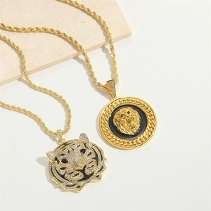 Golden lion and tiger pendant necklaces with twist chain on stone background