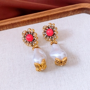 Details von Vintage-Ohrringen mit rosa Steinen und Barockperlen auf einem Holztablett