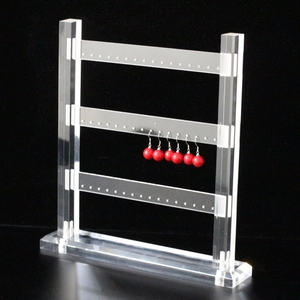 Macro shot of 3-tier clear acrylic earring stand displaying red beaded earrings