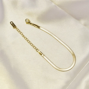 Detail of 18K gold flat snake chain bracelet with lobster clasp and K18 hallmark tag