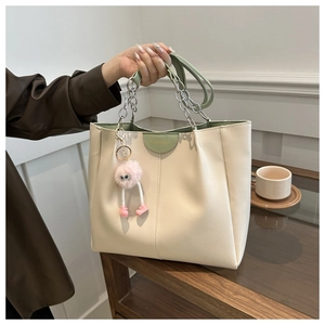 Dettaglio borsa tote beige con manico a catena argento ed etichetta verde moda
