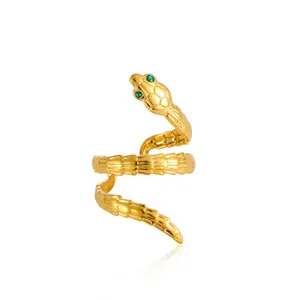 Macro view of gold snake ring featuring green gemstone eyes and textured scales detail