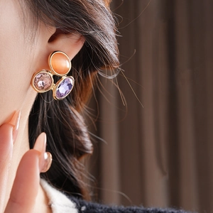 Close-up of vintage tri-color gemstone earrings featuring orange, pink and purple stones