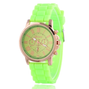 Detail of rose gold watch case and lime green silicone strap with Roman numeral dial