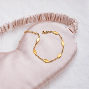 Detail of 18K gold stainless steel marquise link bracelet on soft pink silk fabric