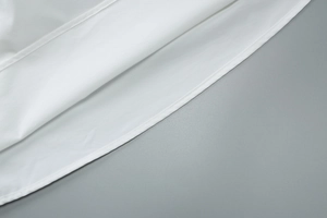 Gros plan détaillé montrant les coutures fines et l'ourlet en tissu doux de la robe blanche