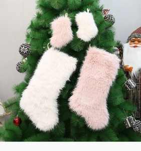 Pink and white plush Christmas stockings hanging on a tree with festive ornaments
