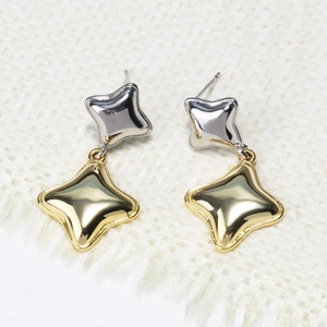 Detail of two-tone starfish earrings in gold and silver finish on white fabric