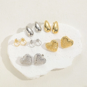 Detailed view of heart-shaped and geometric metal earrings in gold and silver finishes