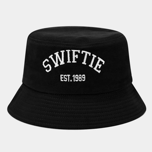 Close-up of white SWIFTIE EST. 1989 embroidery on a black cotton bucket hat fabric