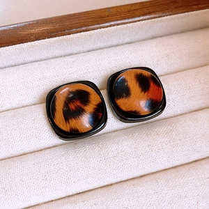 Macro shot of square leopard print resin earrings in a premium jewelry display box