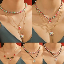 Detailed view of layered Christmas necklaces with Santa, tree, and enamel charms