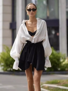Elegant white satin long sleeve blouse with ruffled cuffs and black high waist mini skirt
