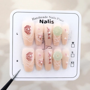 Detail of handmade press-on nails featuring red window patterns and pearl flower accents