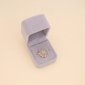 Detail of adjustable gold spiral ring with rotatable metal beads in a velvet jewelry box