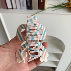 Macro view of medium butterfly hair claw clip featuring pink and blue diagonal stripes