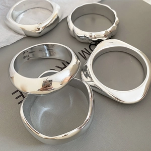 Macro detail of geometric silver bangles with polished mirror finish and metallic texture