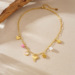 Golden stainless steel necklace with heart pendants, pink beads and rose charms on beige sand