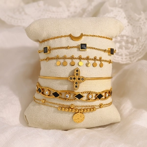 Ensemble de bracelets dorés multicouches avec pendentifs lune et croix sur coussin