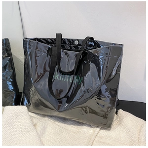 Detail of black glossy tote bag featuring green skillfully text on tweed fabric