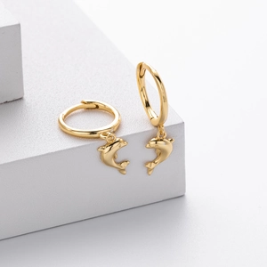 Close-up of golden dolphin hoop earrings on white platform with professional lighting