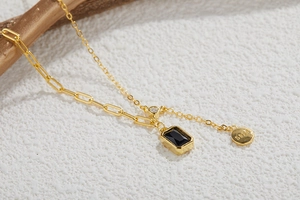 Macro shot of S925 silver necklace with black rectangle gem and round gold pendant