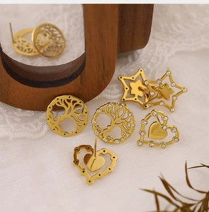 Detailed view of gold plated tree of life heart and star earrings on white lace