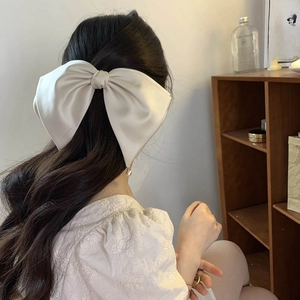 Detail view of large cream satin bow hair clip on model in a French elegant style